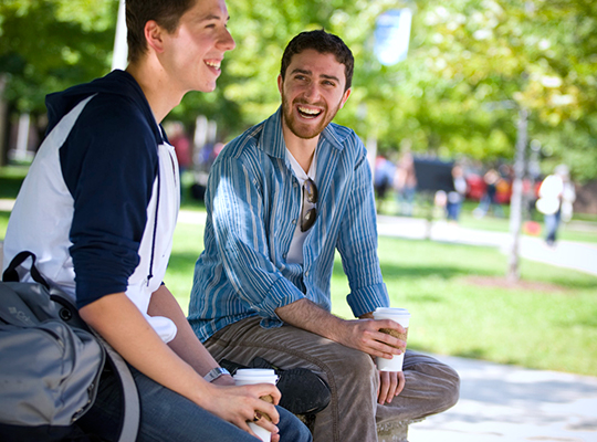 Two students talking and laughing outdoors