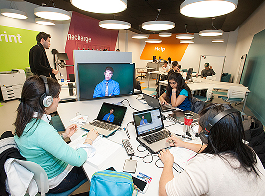Students working with laptops around a monitor in C-Stop