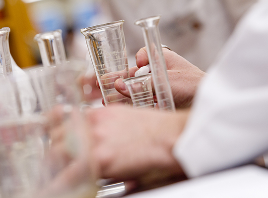 view of hands among chemistry glassware