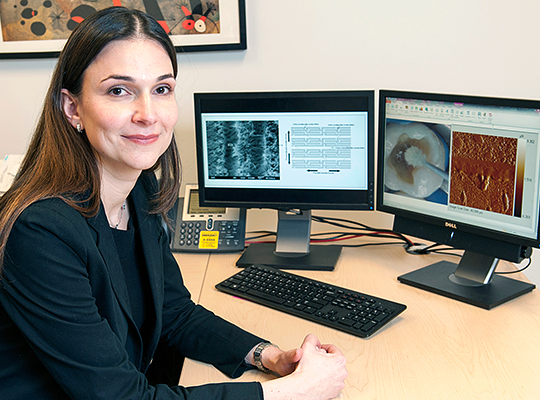 Woman sitting at desk with dentistry imagesd on computer monitors