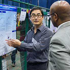 Student explaining his research poster to a judge
